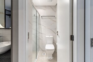 Un baño moderno con cabina de ducha de vidrio, inodoro y lavamanos.