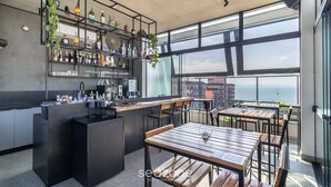 A modern bar area with a bar counter, seating, and a view of the sea. - Spot Jurere sofisticação beira mar SPJs (Florianópolis)