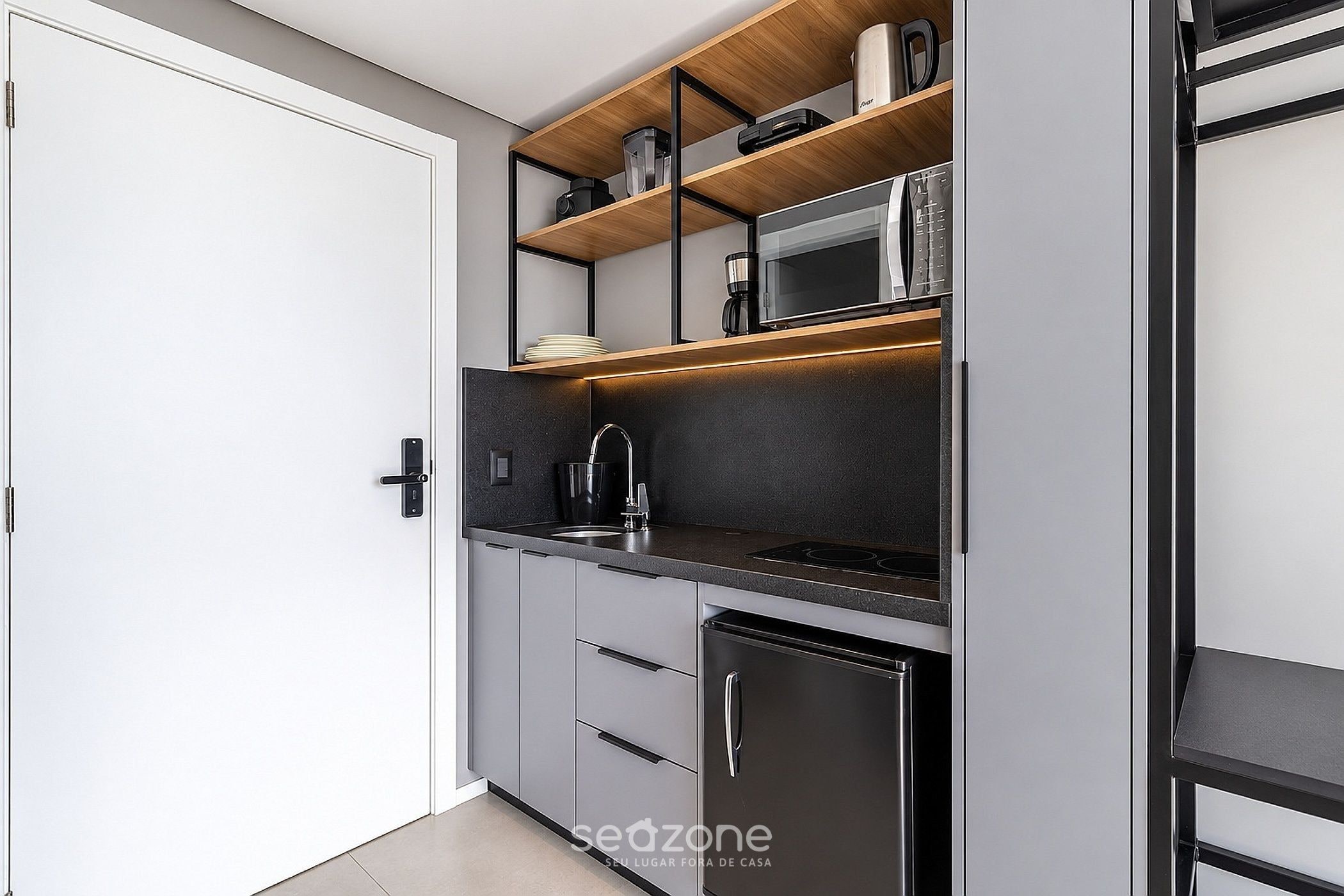 Una cocina moderna equipada con microondas, cafetera y refrigerador.