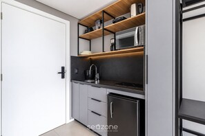A modern kitchen with a built-in microwave, a coffee maker, and a refrigerator. - Spot Jurere sofisticação beira mar SPJs (Florianópolis)