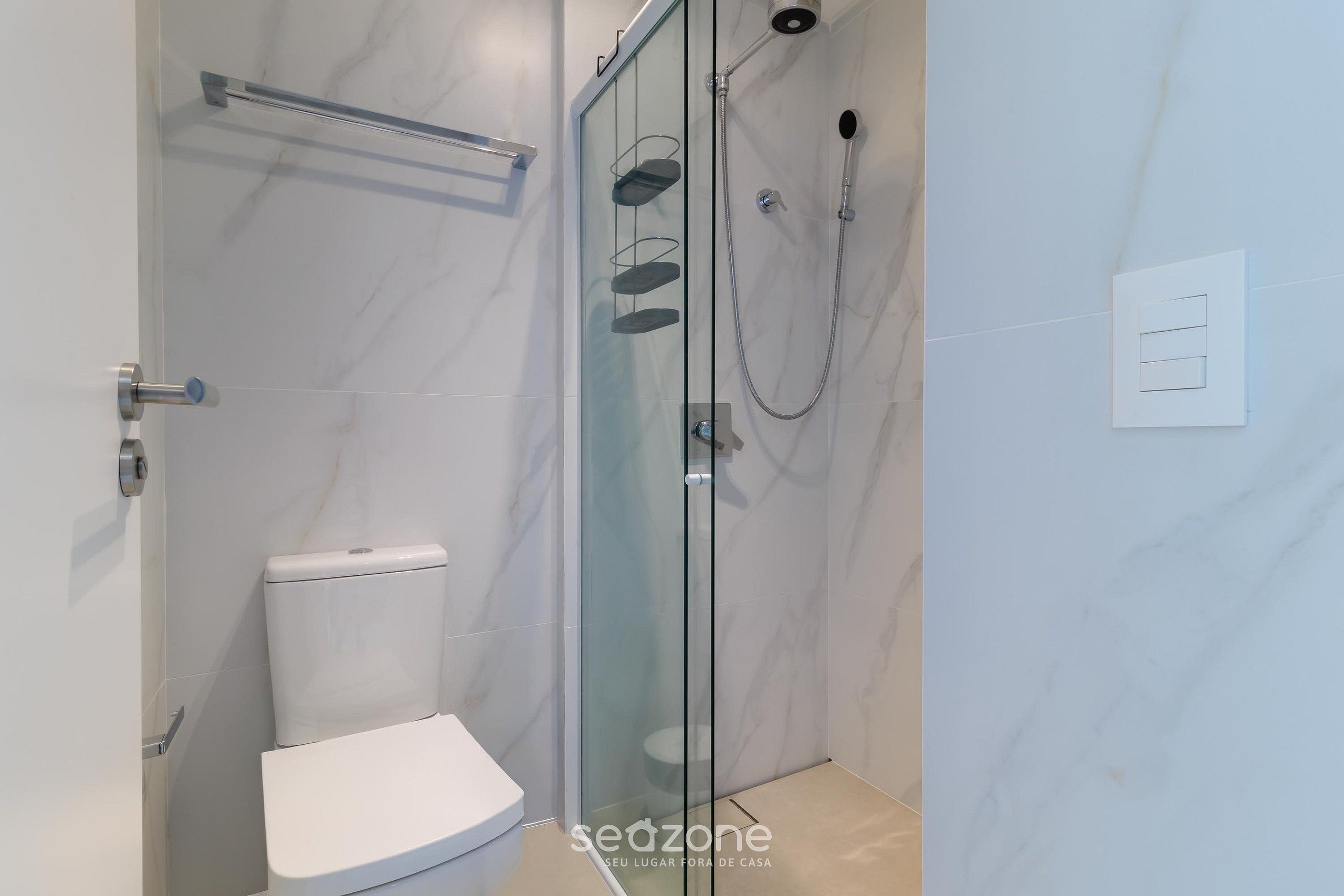 A modern bathroom with a glass shower enclosure, a toilet, and a towel rack.