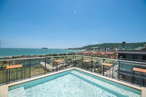 A rooftop pool with a view of the sea and a cityscape.