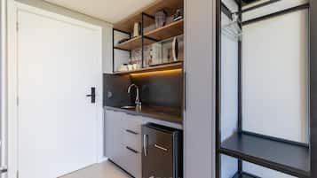 Una cocina compacta con electrodomésticos integrados, un lavamanos y un refrigerador pequeño.