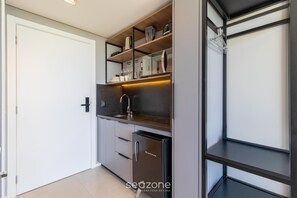 Una cocina compacta con electrodomésticos integrados, un lavamanos y un refrigerador pequeño.