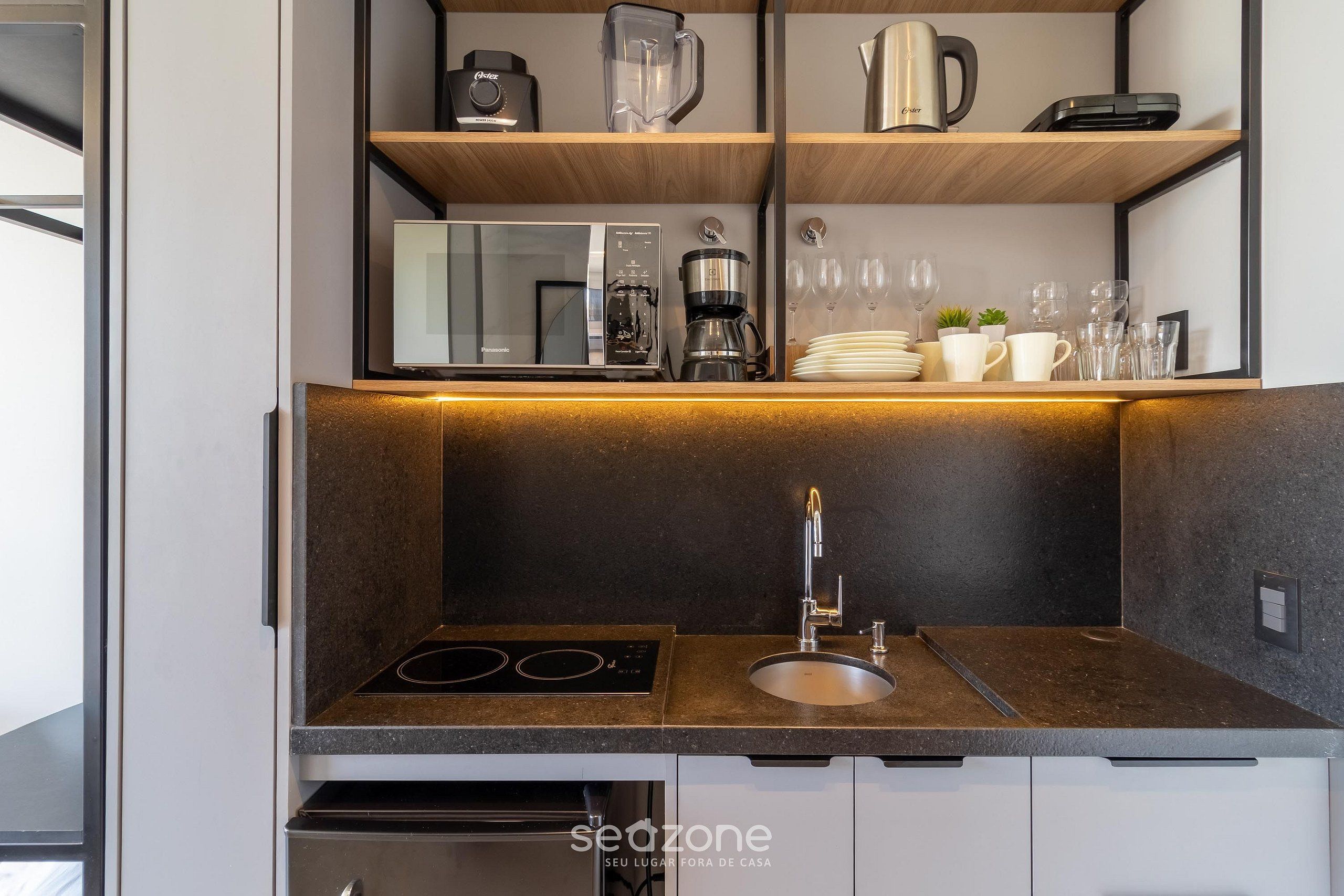 Een keuken met een inbouwoven, een koffiezetapparaat en een spoelbak met een moderne kraan.