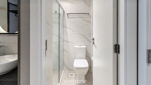 A modern bathroom with a glass shower enclosure, a toilet, and a sink. - Spot Jurere sofisticação beira mar SPJs (Florianópolis)