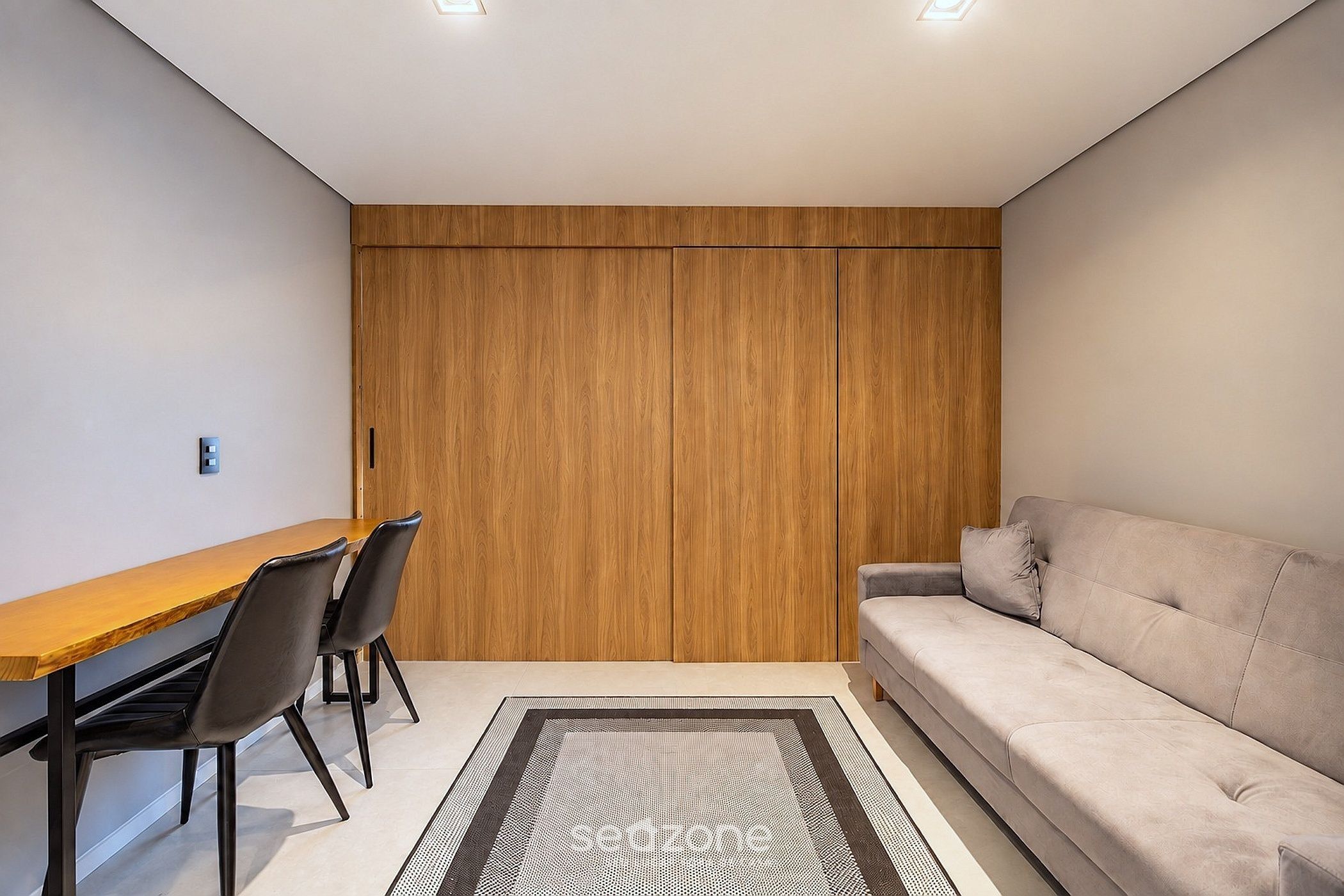 Una habitación moderna con un armario de madera, una mesa de comedor con sillas y un sofá.
