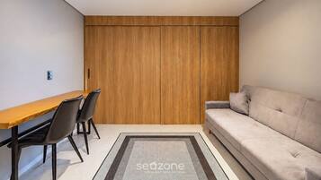 Una habitación moderna con un armario de madera, una mesa de comedor con sillas y un sofá.