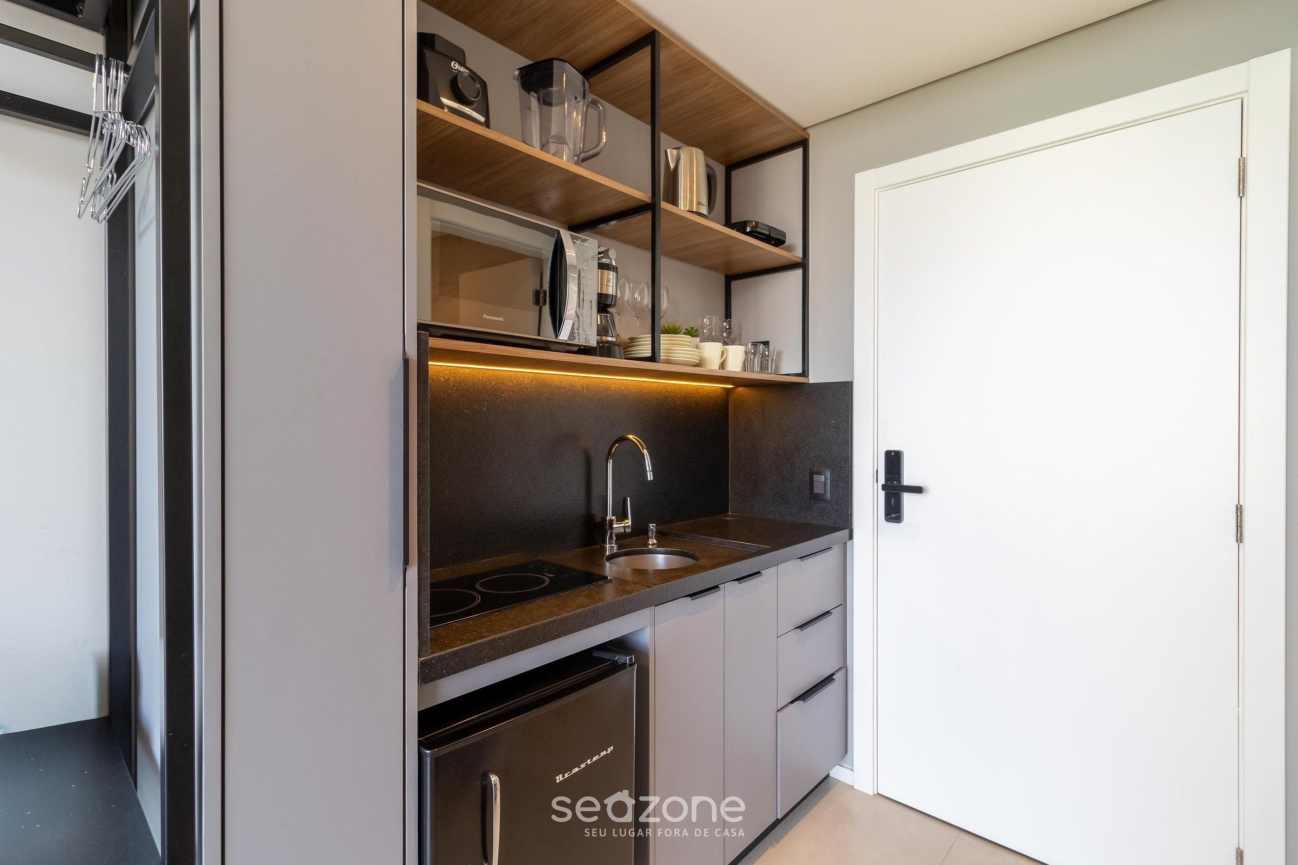 Una cocina compacta con horno empotrado, lavamanos y lavavajillas.