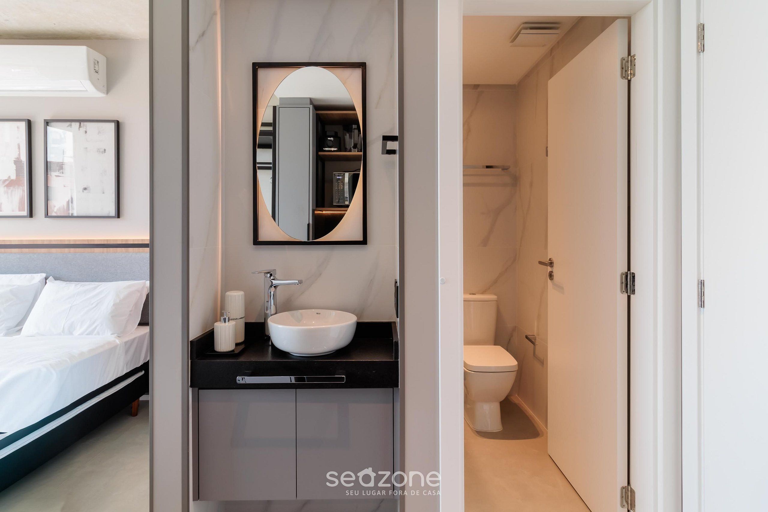 A modern bathroom with a white sink, a mirror, and a toilet.