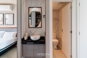 A modern bathroom with a white sink, a mirror, and a toilet.