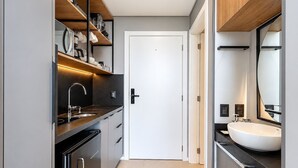 A modern kitchen with a built-in oven, a sink, and a countertop with a coffee machine. - Spot Jurere sofisticação beira mar SPJs (Florianópolis)