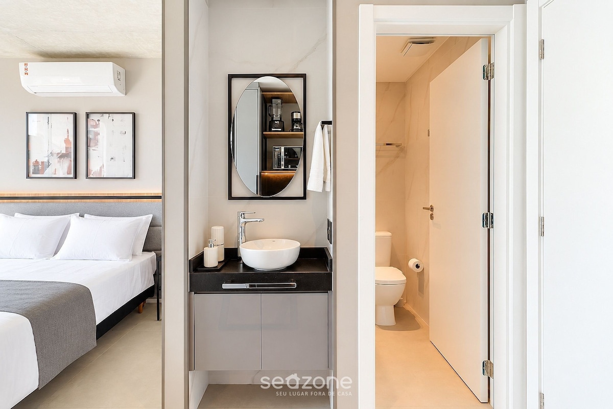 A hotel room with a bed, a bathroom with a sink and mirror, and a door leading to another room.
