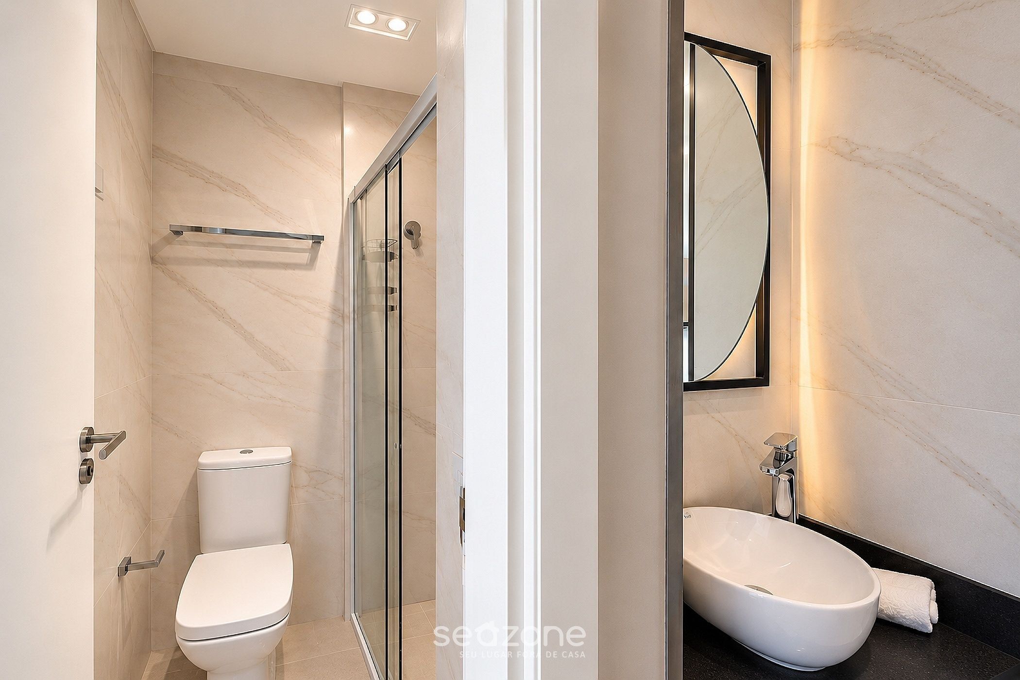 A modern bathroom with a toilet, a glass shower enclosure, and a sink with a mirror.