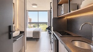 A modern kitchen with a built-in stove, a sink, and a large window offering a view of the outdoors. - Spot Jurere sofisticação beira mar SPJs (Florianópolis)