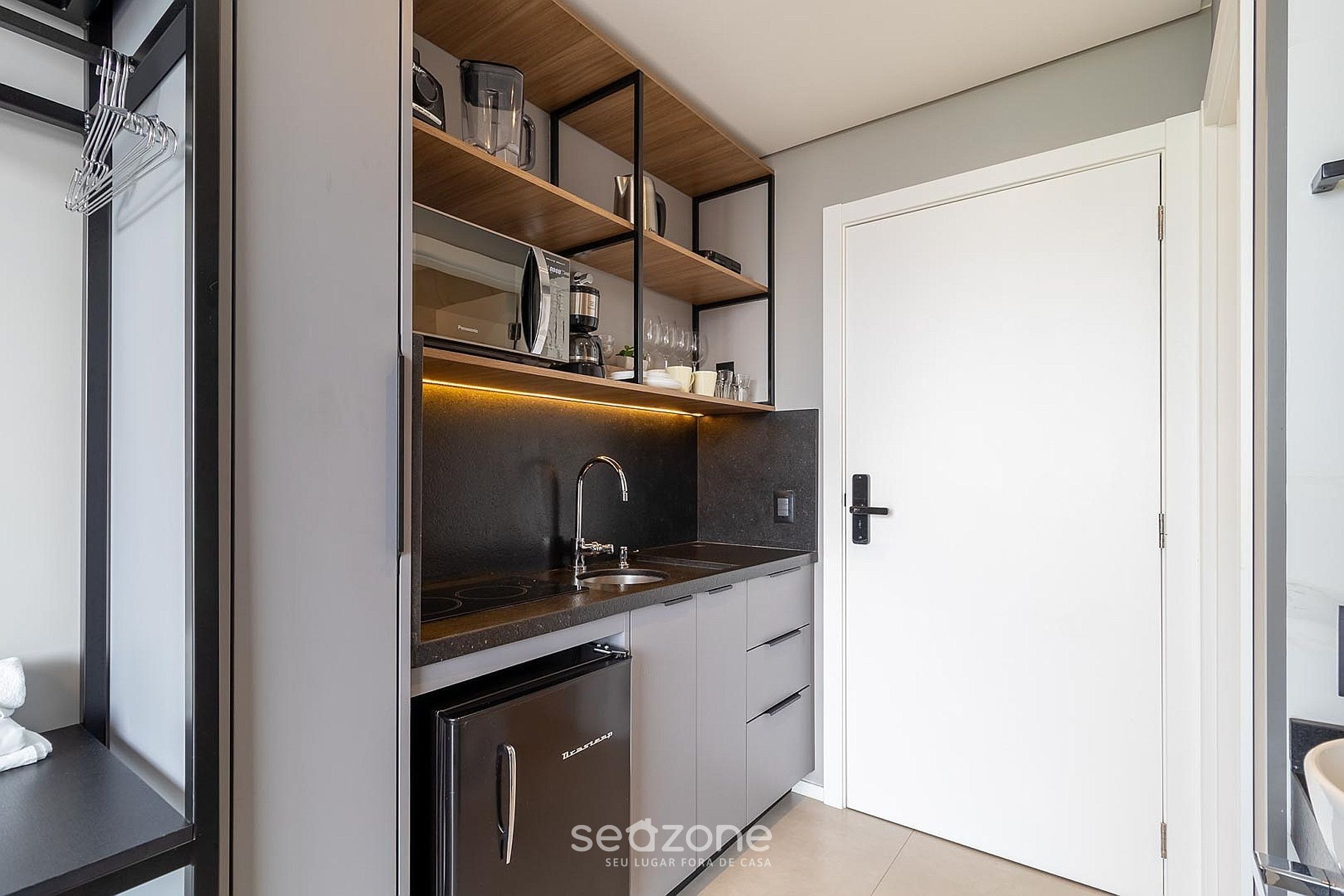 A modern kitchen with a built-in oven, a sink, and a coffee machine.