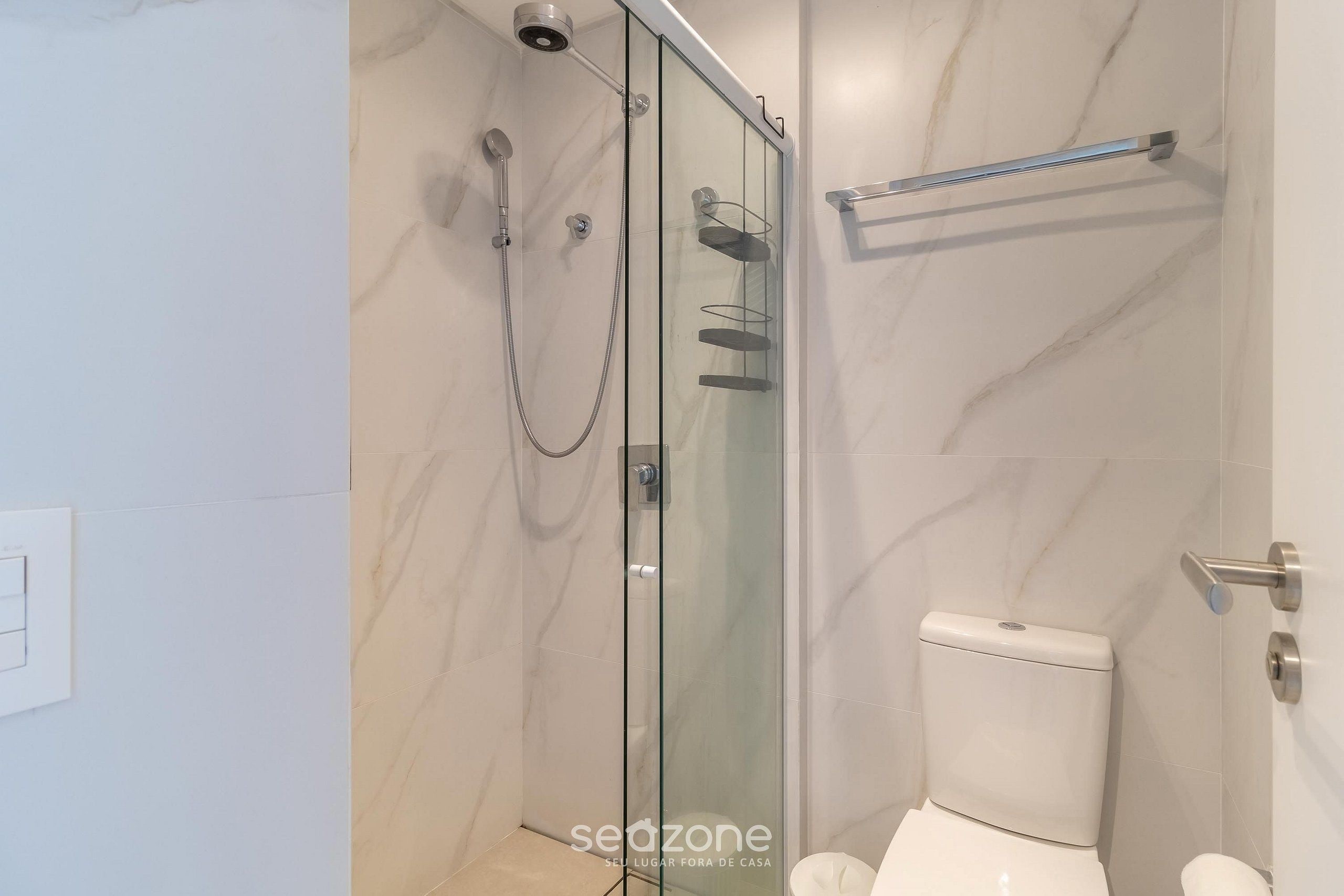 A modern bathroom with a glass-enclosed shower, a toilet, and a towel rack.