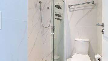 Un baño moderno con ducha envuelta en vidrio, inodoro y toallero.