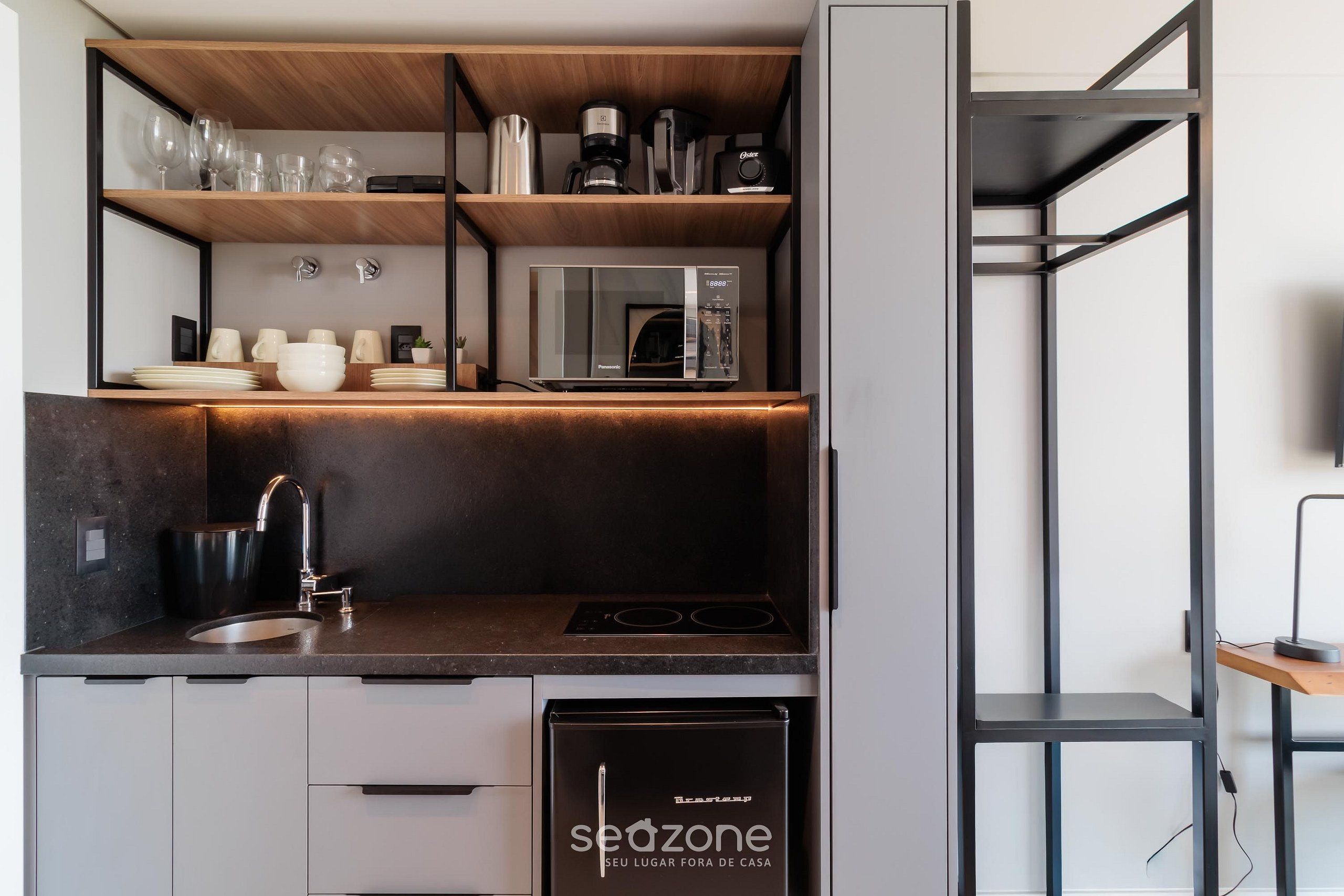 A compact kitchen with a built-in microwave, a sink, and a stove.