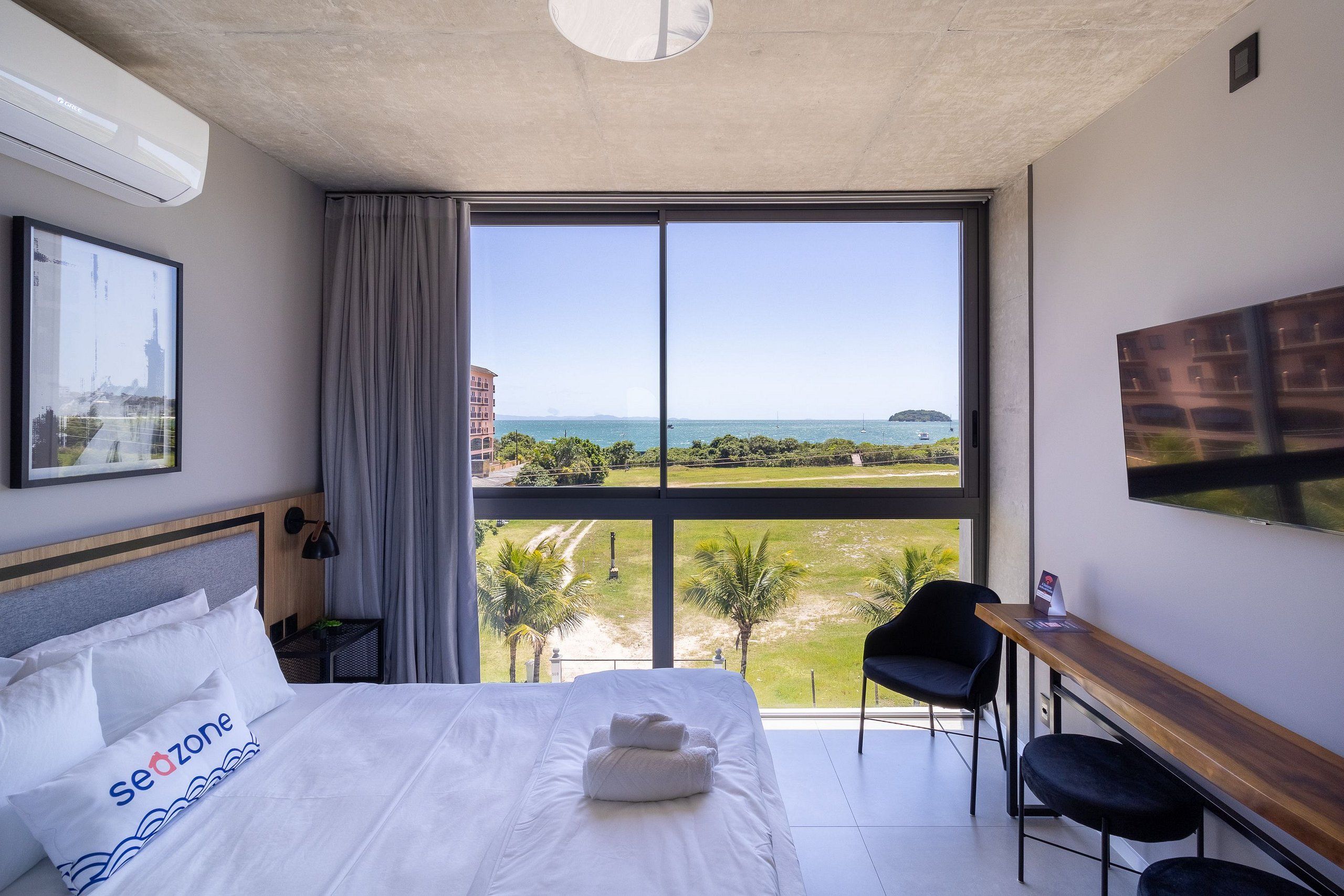 Habitación de hotel con una cama grande, un escritorio, una silla y vistas al mar.