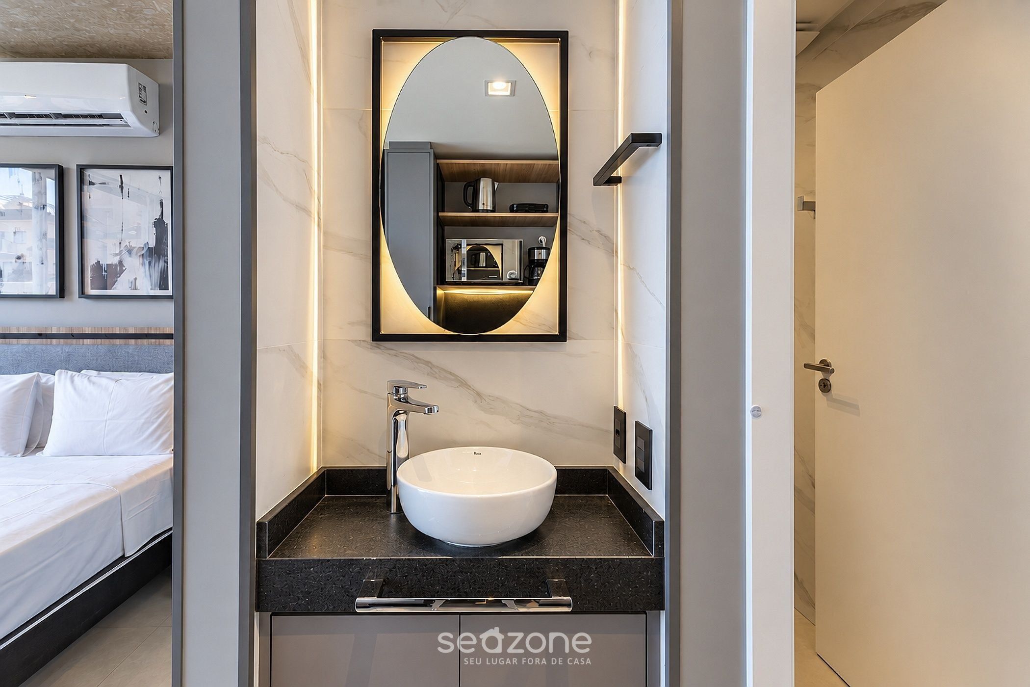 Un baño moderno con un lavabo blanco, un espejo grande y una encimera negra.
