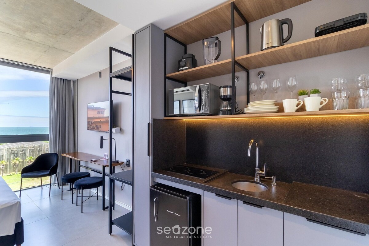 A modern kitchen with a built-in oven, a sink, and a coffee maker. There is a dining area with a table and chairs.