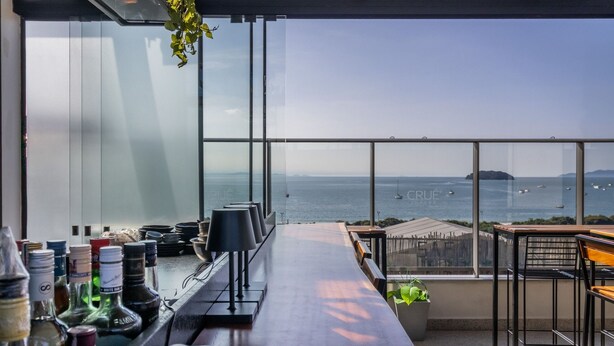A bar with a view of the ocean and distant land. - Spot Jurere sofisticação beira mar SPJs (Florianópolis)
