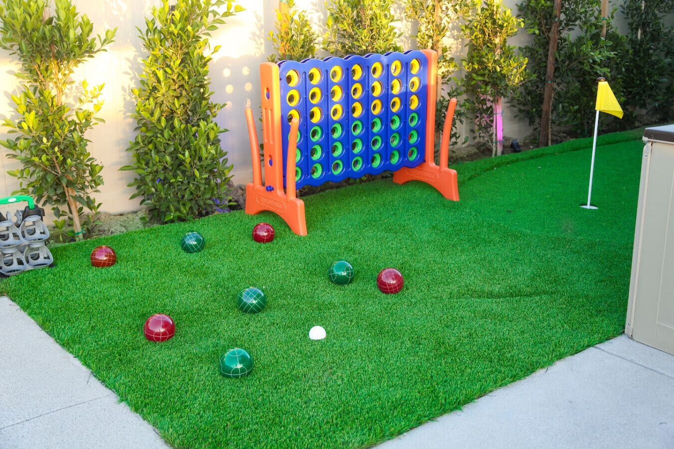 Ein Garten mit Kunstgrashalm, einem Boccia-Spielfeld und einer gelben Flagge.