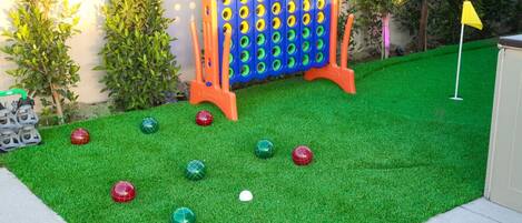 Ein Garten mit Kunstgrashalm, einem Boccia-Spielfeld und einer gelben Flagge.