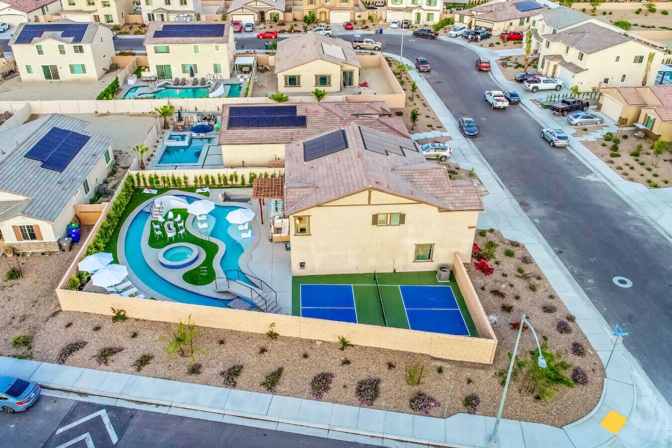 Zona residencial con piscina, cancha de tenis y paneles solares en los tejados.