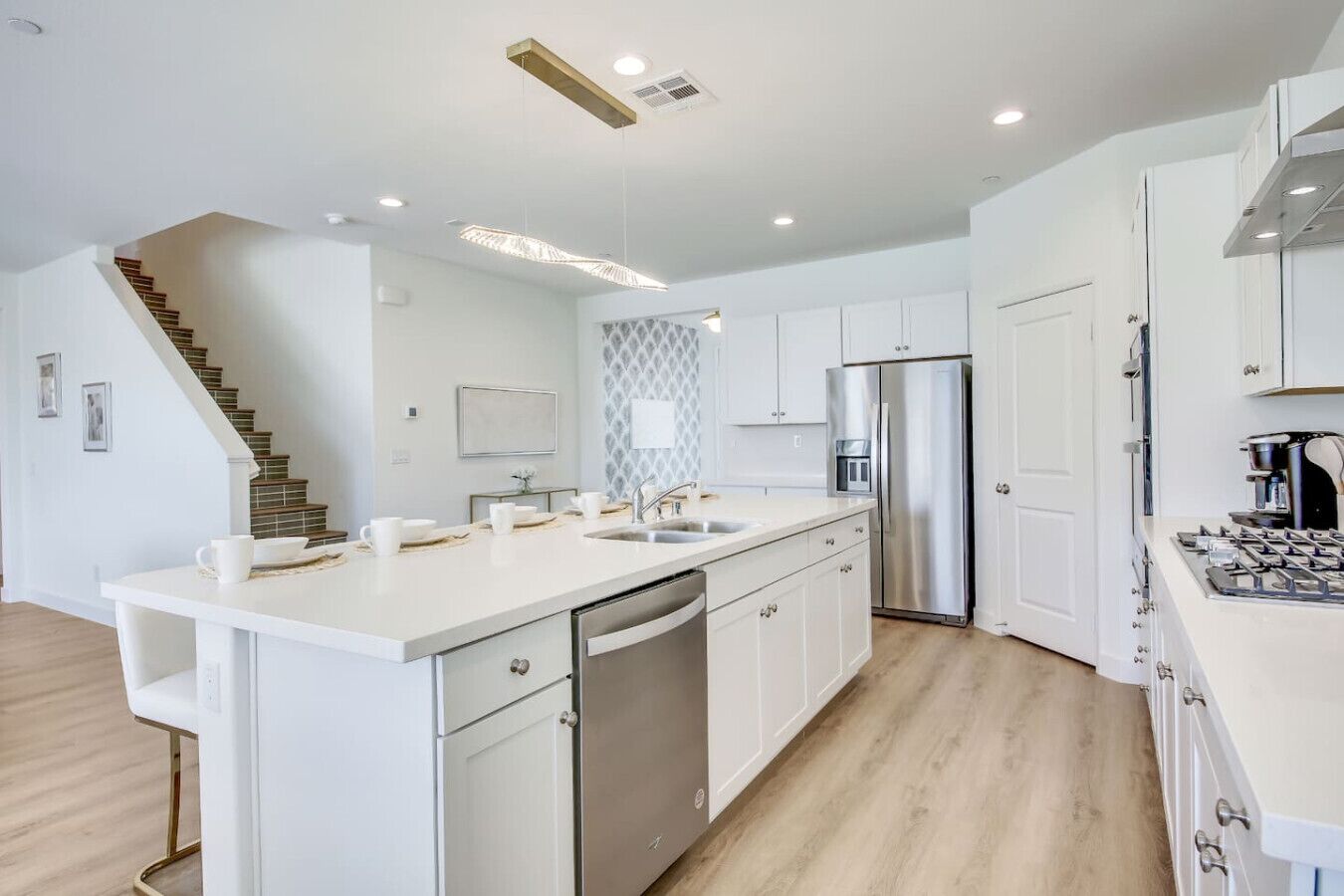 Una cocina moderna con armarios blancos, un refrigerador de acero inoxidable y un lavavajillas integrado.