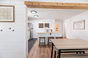 A modern kitchen with white cabinetry, a wooden ceiling, and a dining area with a table and stools. - The Harbor @ Lighthouse Lodge – Lakefront Home with Covered Porch & Boat Slip Ac (Kimberling City)