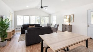 A spacious living room with a dark sofa set, a wooden coffee table, and a ceiling fan. - The Harbor @ Lighthouse Lodge – Lakefront Home with Covered Porch & Boat Slip Access (Kimberling City)