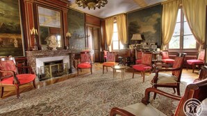 A grand room with a fireplace, ornate furniture, and large windows with curtains. - Château de Montclair (POMMIERS)