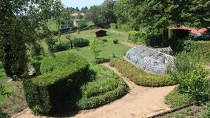 A greenhouse surrounded by neatly trimmed hedges and a dirt path. - Château de Montclair (POMMIERS)