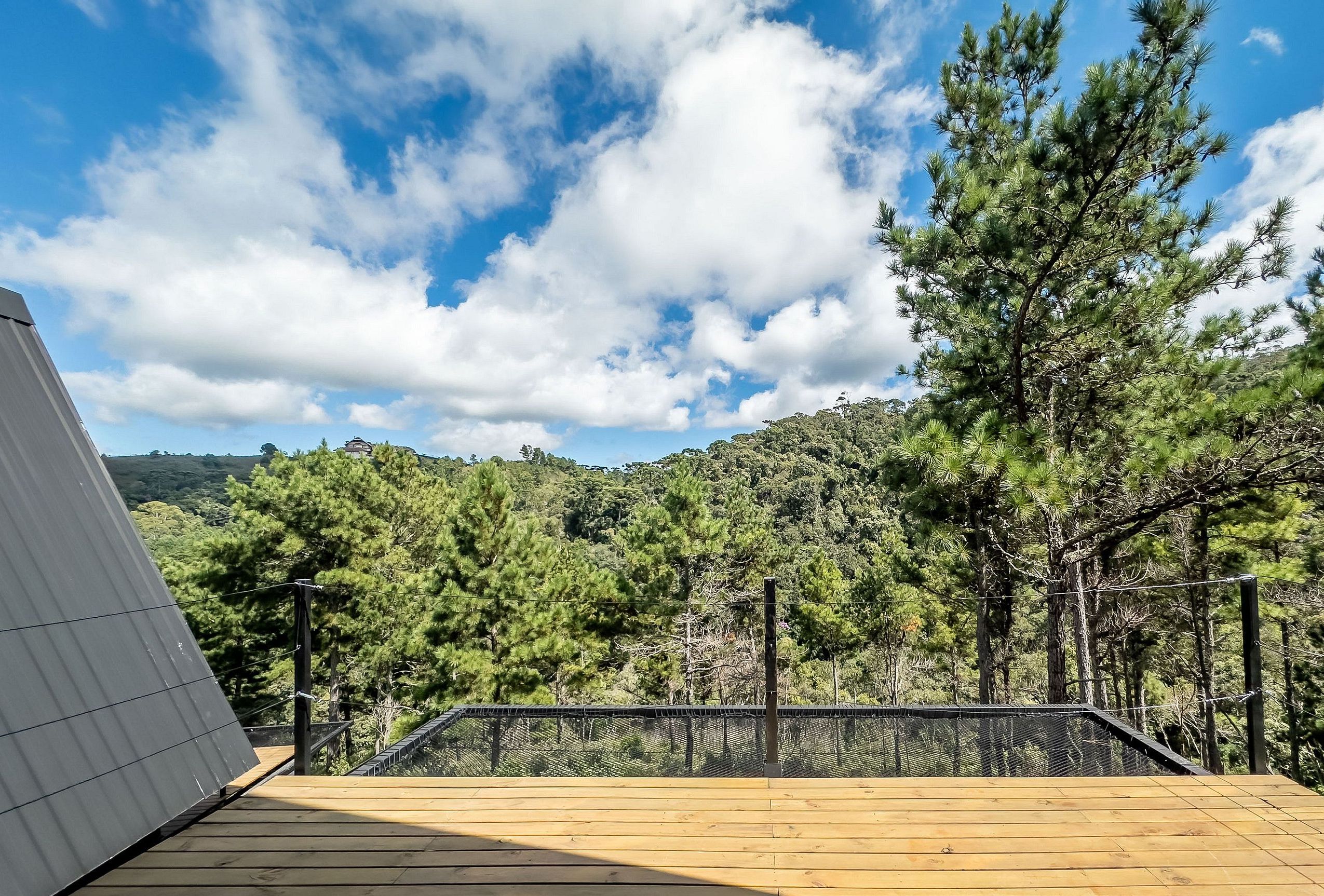A wooden deck with a metal railing overlooking a forested hillside.