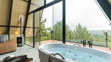 Un intérieur moderne avec un jacuzzi, un plancher en bois et une grande fenêtre donnant sur un paysage pittoresque.