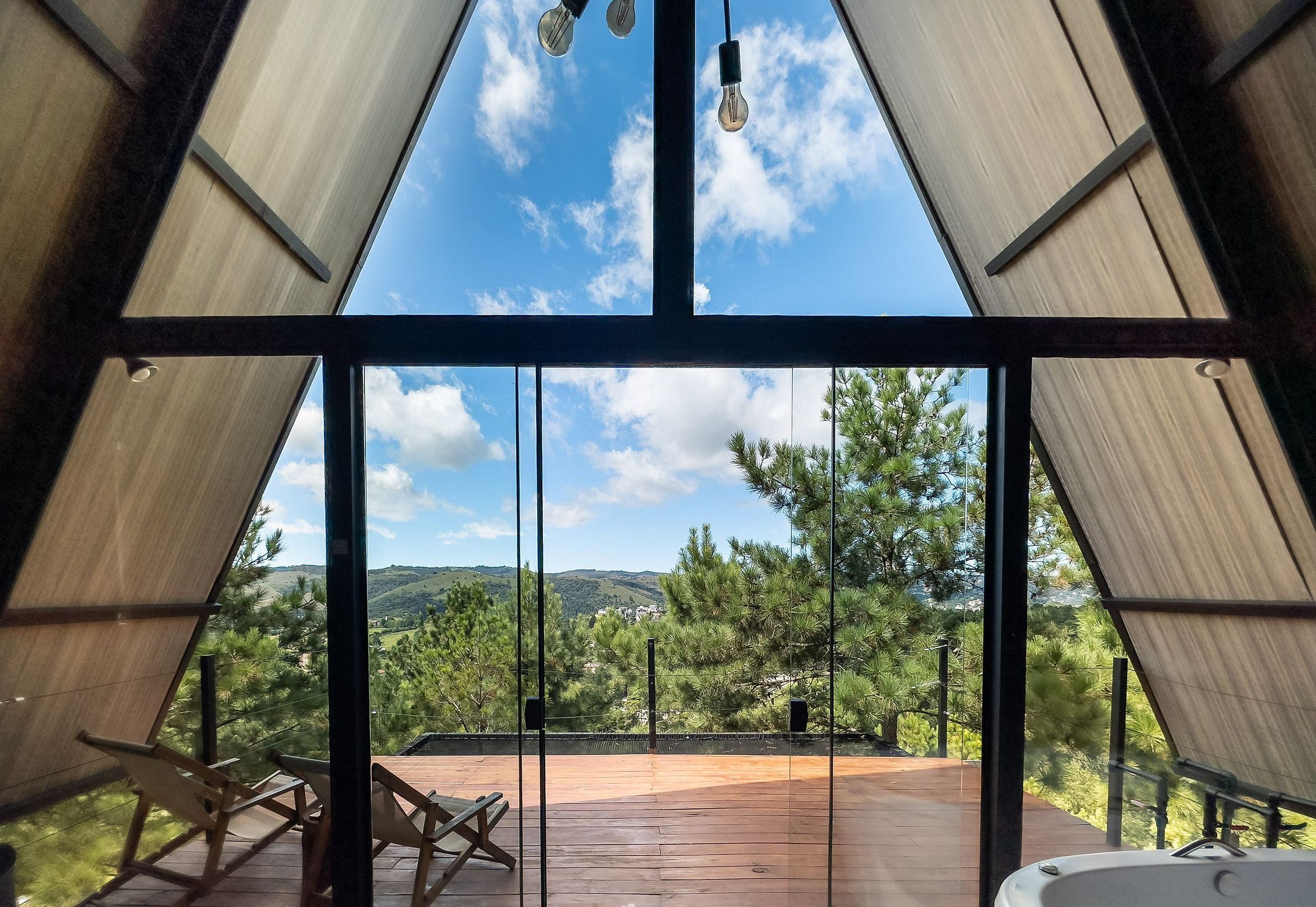 A modern interior with a large glass window offering a view of a wooden deck and surrounding greenery.