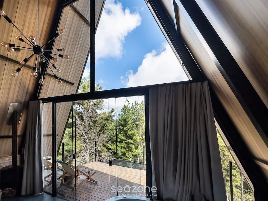 A modern interior with a large window, wooden deck, and a ceiling light fixture.