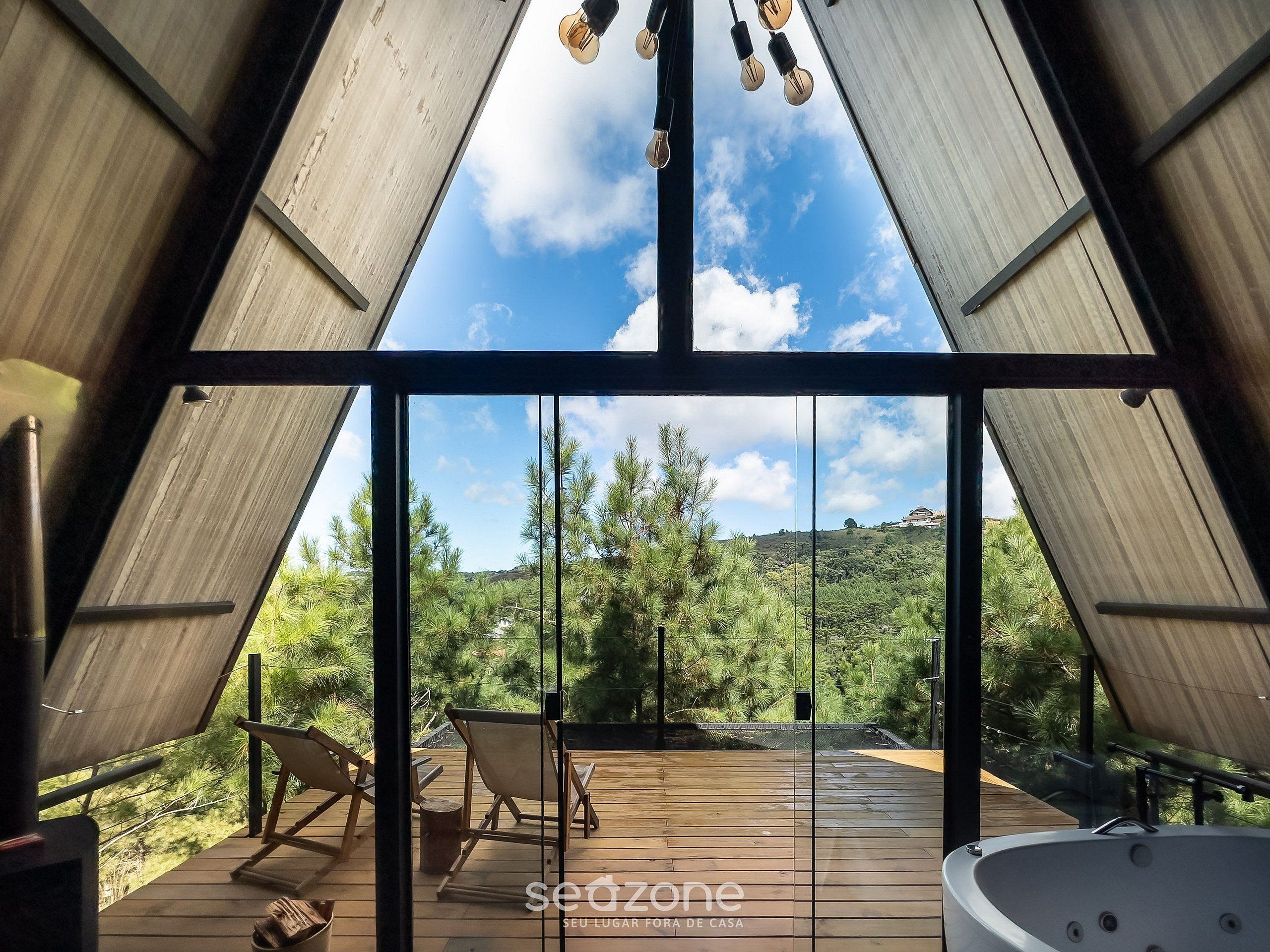 A modern interior with a large glass window, wooden deck, and a hot tub.
