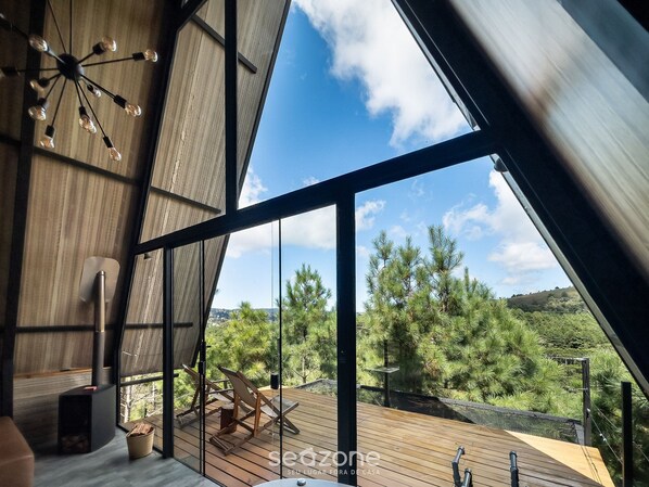 A modern interior with a large window, wooden flooring, and a ceiling light fixture.