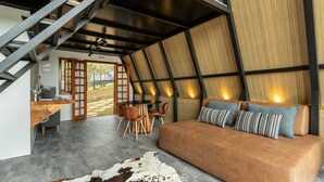 A modern interior with a sofa, dining area, and staircase. - Chales Naturale - Campos do Jordão - CNA (Campos do Jordão)
