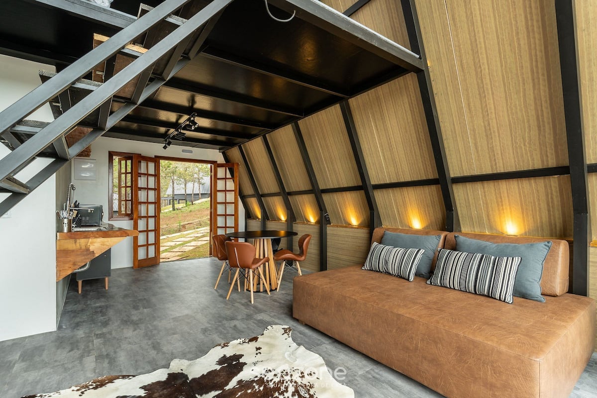 A modern interior with a sofa, dining area, and staircase.
