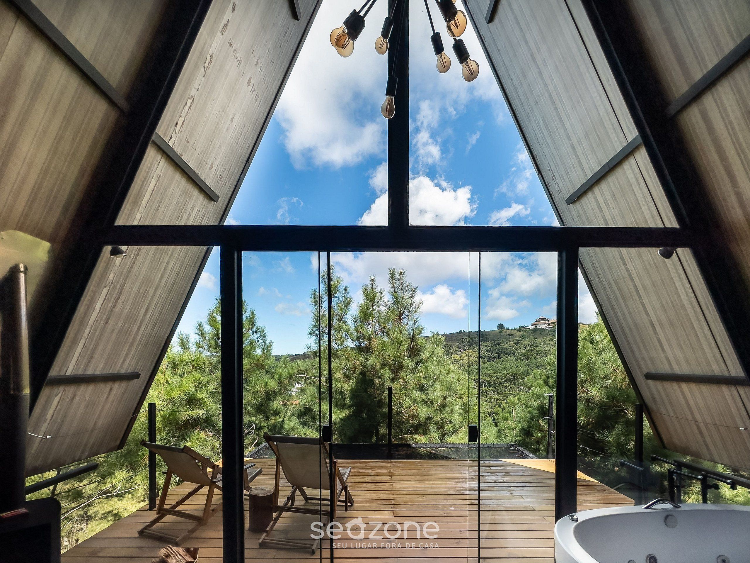 Un interior moderno con un gran ventanal, terraza de madera y bañera de hidromasaje.