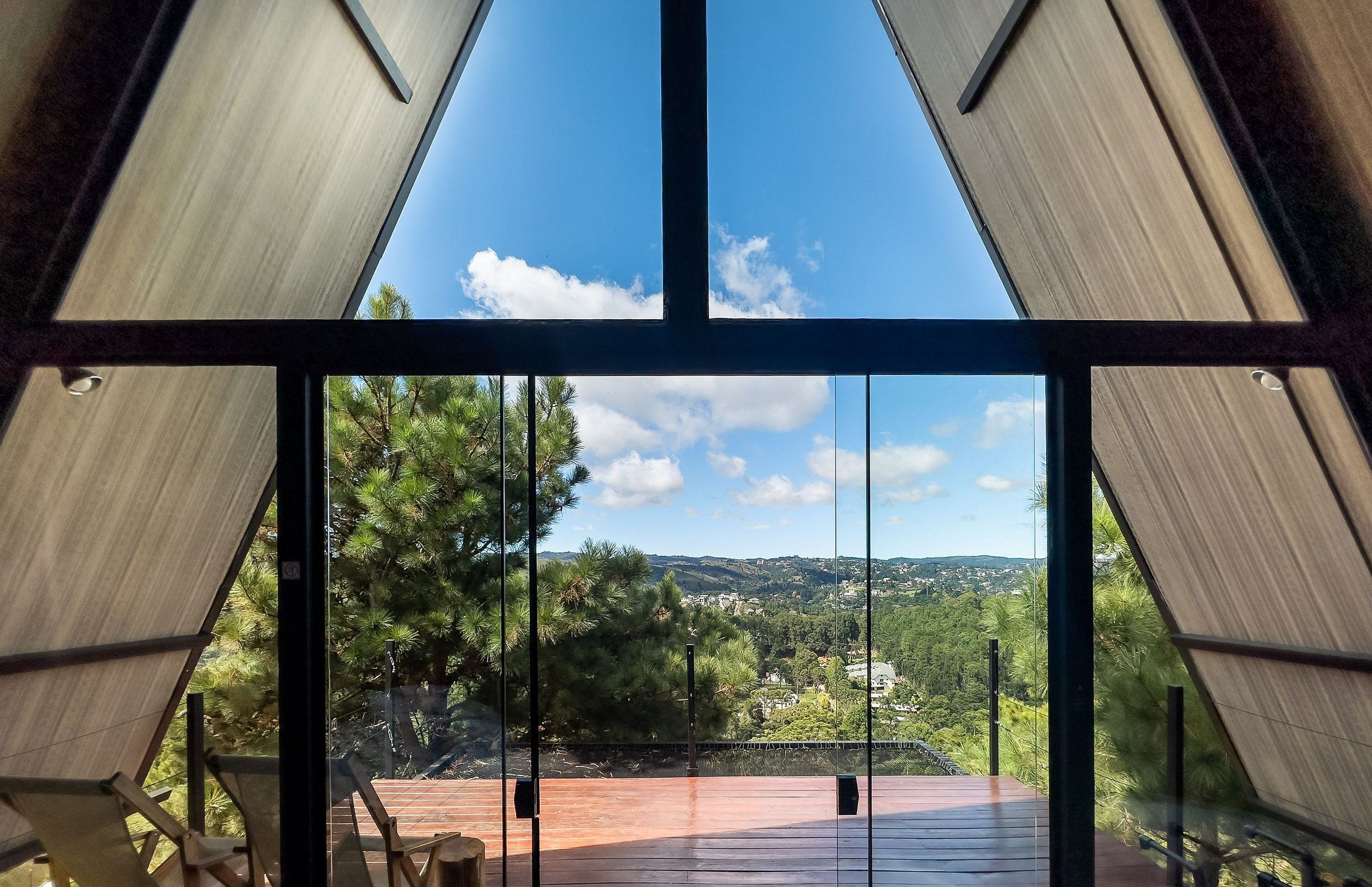 A modern interior with large glass windows offering a view of a lush landscape and distant town.