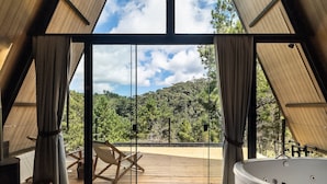 A modern interior with a large glass door leading to an outdoor deck, a wooden deck, and a hot tub. - Chales Naturale - Campos do Jordão - CNA (Campos do Jordão)