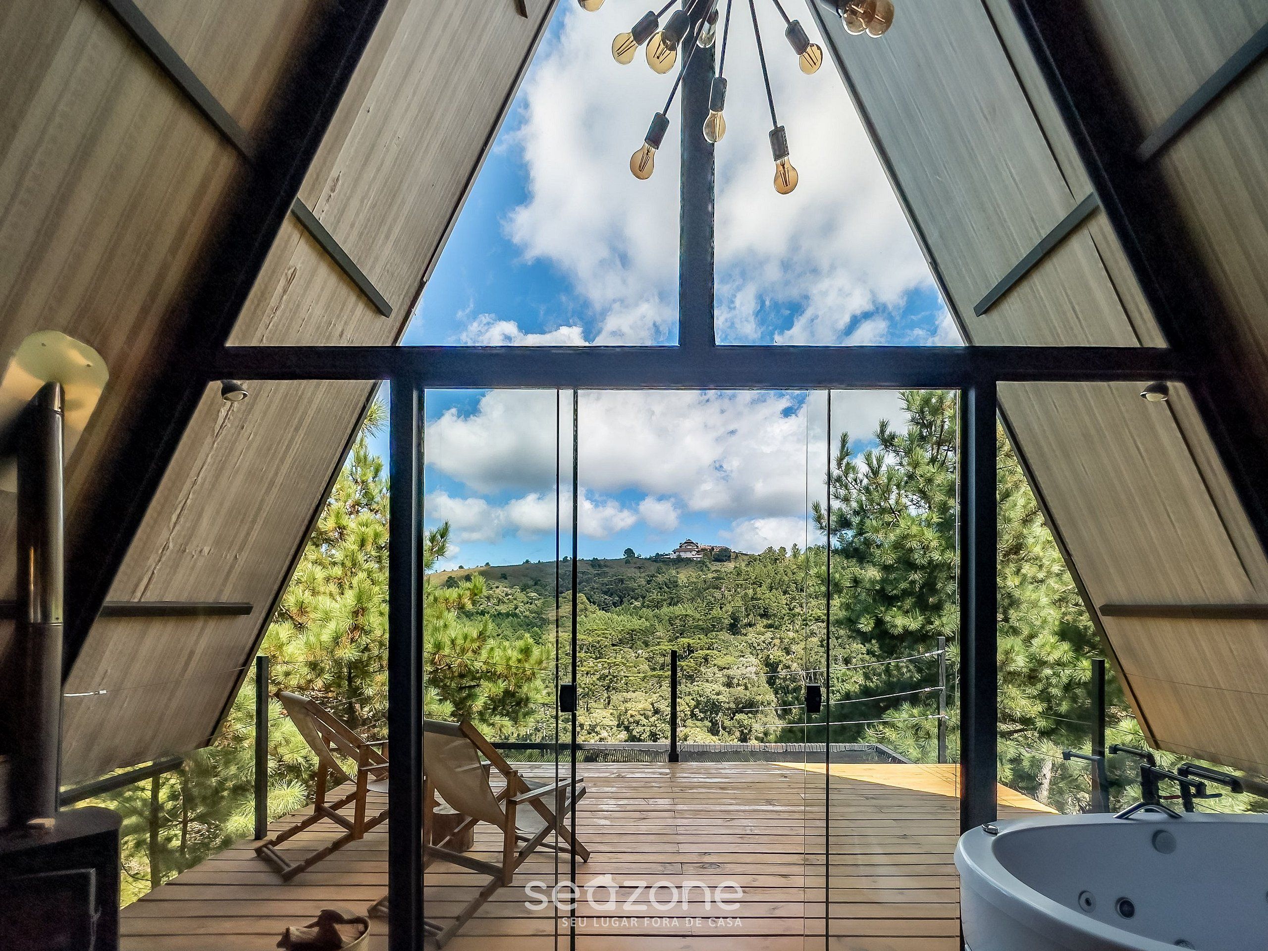 A modern interior with a large glass window, wooden deck, and a hot tub.