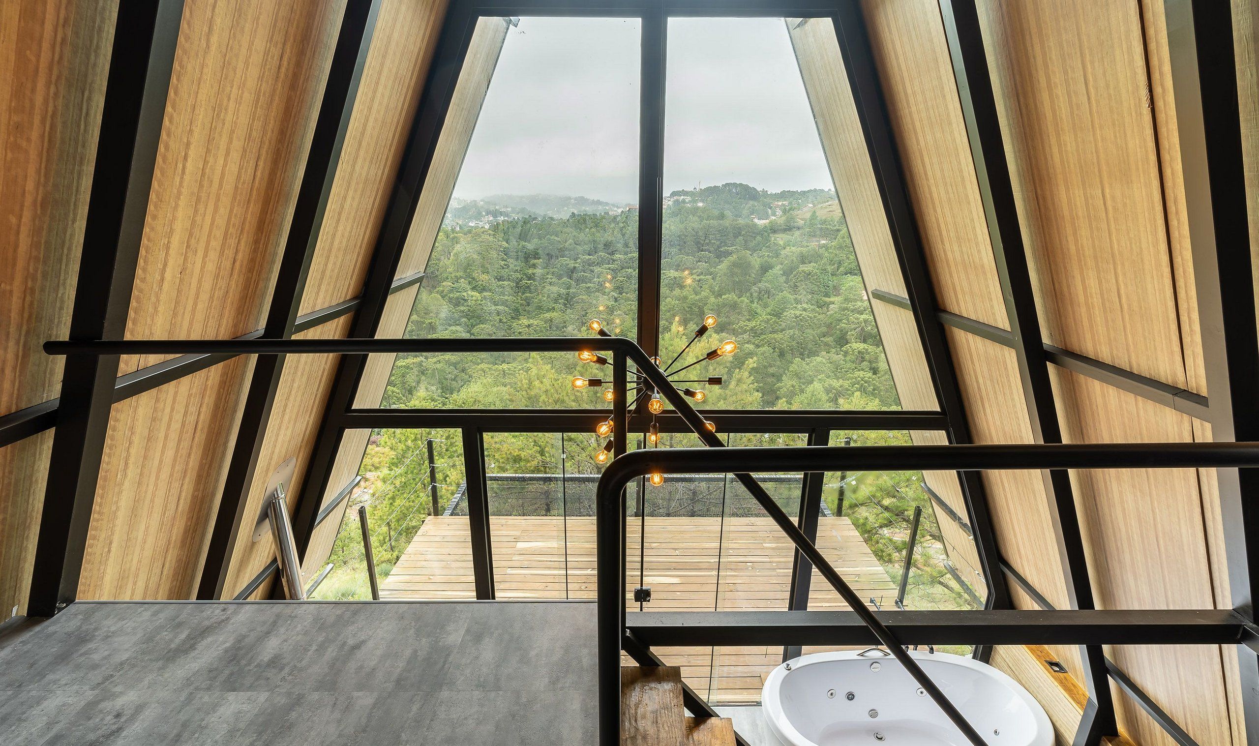 Una habitación con un ventanal grande, una terraza de madera afuera y una bañera.