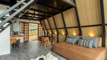 A modern interior with a sofa, dining area, and staircase.