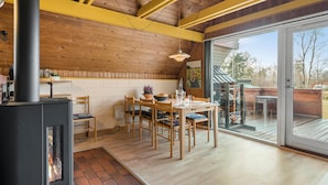 Uma sala de jantar acolhedora com uma mesa e cadeiras de madeira, lareira e uma grande porta de vidro deslizante que dá para um deck externo.